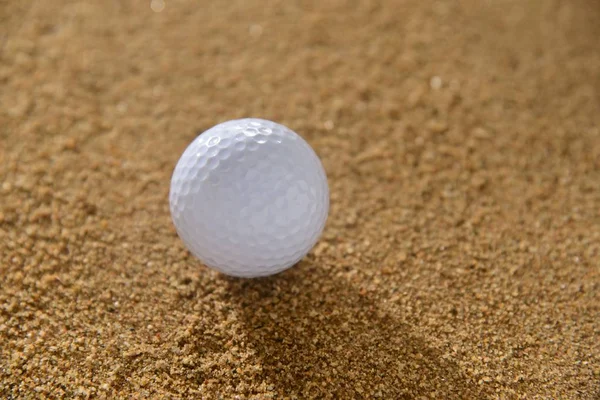 Golf ball op zand — Stockfoto