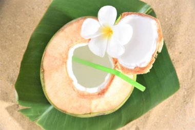 Genç Hindistan cevizi meyve suyu muz yaprağına hizmet vermeye hazır yerleşmek Denizde kum