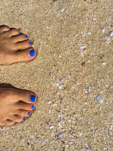 Füße mit blauer Pediküre am gelben Sandstrand, Frauenfüße am Sandstrand — Stockfoto