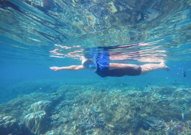 Kadın denizaltı Yüzme kostüm ve tam yüz maskesi içinde yüzüyor.