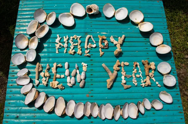Feliz Año Nuevo inscripción hecha por los corales en la mesa de madera . —  Fotos de Stock