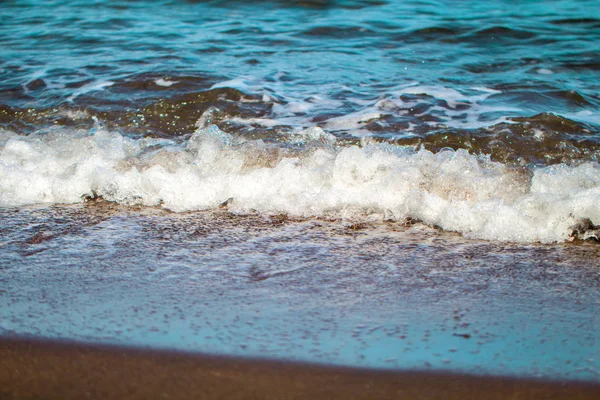 Blauwe zeewater over gember bruin zandstrand. Ontspannen zee wave surf over kust. — Stockfoto