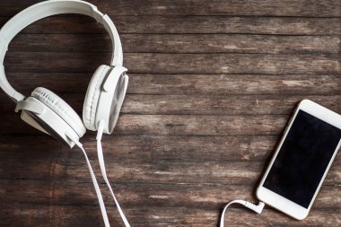 Beyaz kulaklık ve smartphone ahşap arka plan üzerinde. Afiş için düz yatıyordu kompozisyon