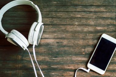 Beyaz kulaklık ve smartphone ahşap arka plan üzerinde. Gri ahşap arka plan metin yer ile.