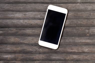 Rustik ahşap masa üstünde beyaz smartphone. Eski püskü şık arka plan üzerinde siyah ekran smartphone.