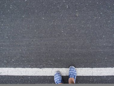 Gri asfalt beyaz çizgi işareti ve kadın ayakları ayakkabı. Asfalt üzerinde beyaz çizgiyi çift ayakkabı ayaklarda kız. Yol işareti üstten görünüm. Trafik kuralları afiş şablon metin yer ile. Seyahat Ayakkabı
