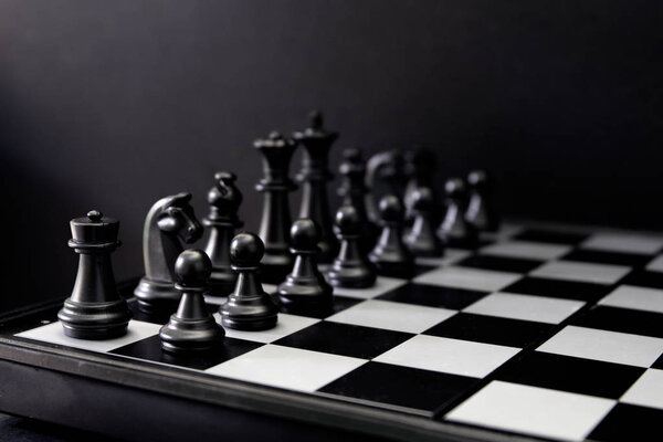 Black chess figures on board. Black chess set in order for game start. Black chess figures row on checkered board. Chess game begins. Checkmate game banner template. Intellectual sport. Tactic game