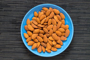 Badem koyu zemin üzerine mavi plaka. Kahverengi gıda için badem.