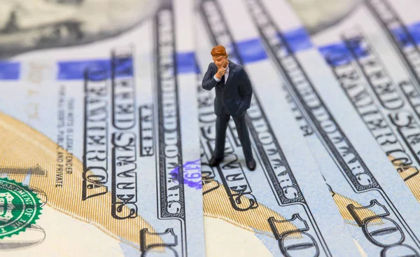 Businessman thinking of strategy. Businessman figurine on dollar banknote