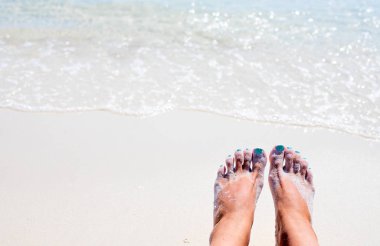 Kadın ayakları sıcak güneşli plaj üzerinde. Rahat yalınayak turist deniz tarafından. Seaside afiş şablon.