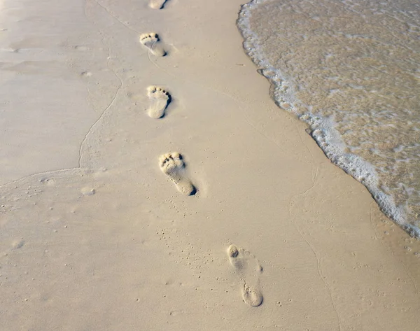 Çıplak ayakla zinciri ıslak beyaz kum üzerinde yürümek. Beach view fotoğraf. Plaj ayak izleri. — Stok fotoğraf