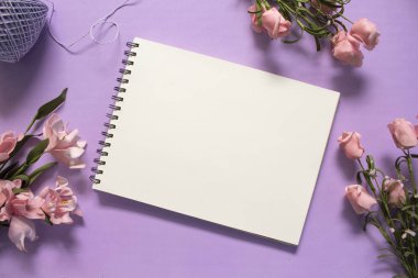 Gül ve boş sayfa düz mor zemin üzerinde yatıyordu. Romantik Pembe çiçek buketi.