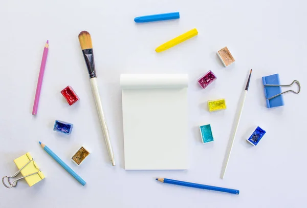 Notepad and art tools on white background.