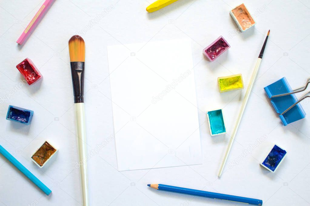 White paper notepad and drawing art supplies. Colorful artistic flat lay on white background.