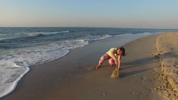 Mujer construye un castillo de arena en la playa — Vídeo de stock