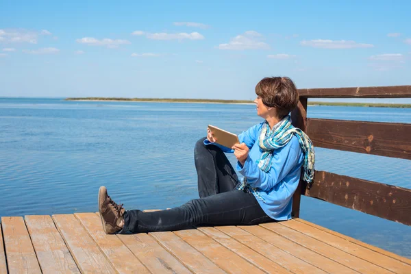Woman relaxing on sea, using tablet pc