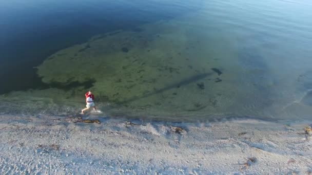 Homme courant le long de la ligne de surf — Video