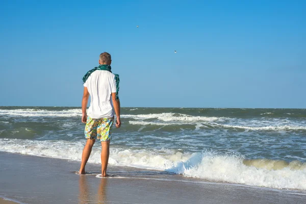 Mężczyzna na plaży oglądanie fale — Zdjęcie stockowe