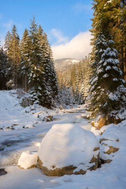 Gün batımı sırasında kış ormandaki donmuş nehir