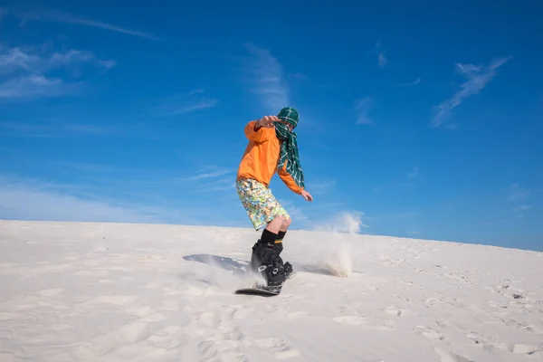Snowboarder, wearing a scarf riding in desert. Wide angle