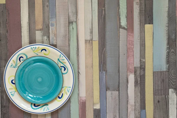 Platos de colores diferentes en la esquina de la mesa de madera — Foto de Stock
