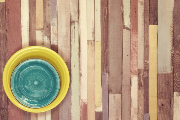 Placas turquesa y amarilla en la esquina de la vieja mesa de madera — Foto de Stock