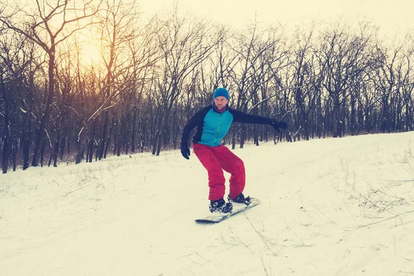 Vousatý muž je jízda na snowboardu v zimě lese — Stock fotografie