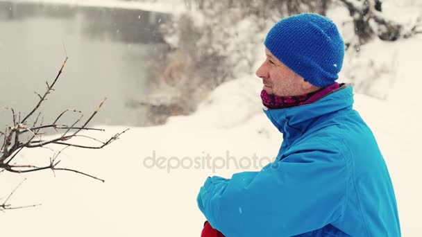 Бородатый мужчина сидит на берегу озера — стоковое видео