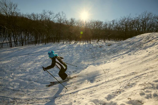 Žena sjezdového lyžování v paprscích zapadajícího slunce — Stock fotografie