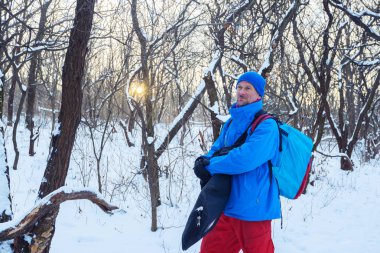 Freeride donatımı adamla gülümseyen kış ormanının içinde gider