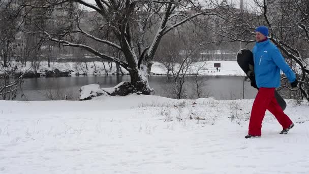 Bärtiger Mann mit Snowboard geht auf die Piste und springt vor Freude — Stockvideo