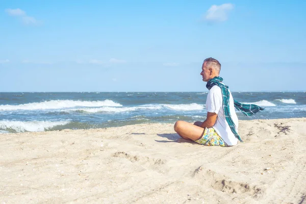 Dreaming człowiek siedzi na plaży i patrząc na fale — Zdjęcie stockowe