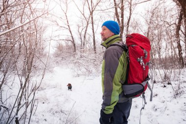 Sakallı adam ile küçük köpek kış ormanda yürüyor