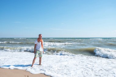 Gülümseyen adam sahilde duran