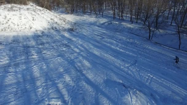 Luftfoto af kvinde skiløb ned ad bakke i lyset af vintersolen – Stock-video