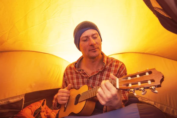 Portret mężczyzny, turysta, odpoczynek w namiocie z ukulele — Zdjęcie stockowe