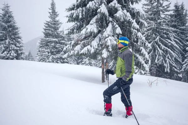 Erkekte koruyucu gözlük ve gider kar ayakkabıları yukarı bir tepe — Stok fotoğraf