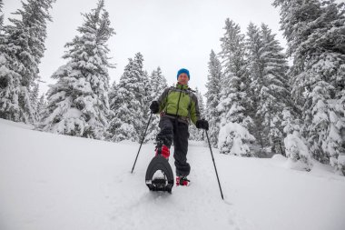 Mutlu bir adam kar ayakkabıları tepeden aşağı gider 