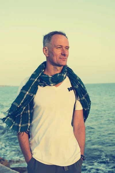 Hombre sonriente viajero en la playa en el día ventoso — Foto de Stock