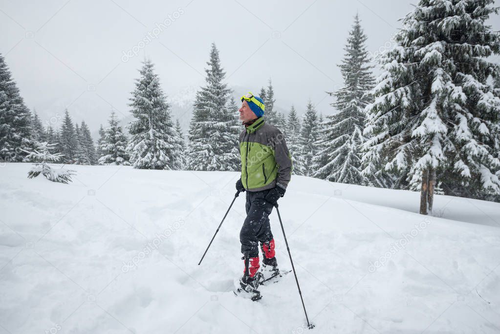 Man in snowshoes enjoying life while traveling in the winter mou