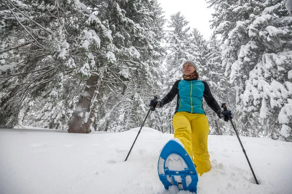 Щаслива жінка насолоджується прогулянкою в снігоступах — стокове фото