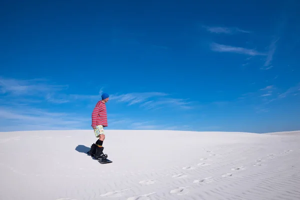 Człowiek w kolorowy koszula slajdy w dół na snowboardzie na piasku dun — Zdjęcie stockowe