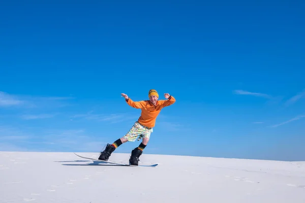 Joyful man rides on the snowboard in desert — Stock Photo, Image