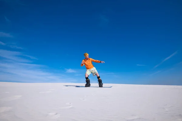Hombre deportivo monta en la tabla de snowboard en las dunas de arena — Foto de Stock