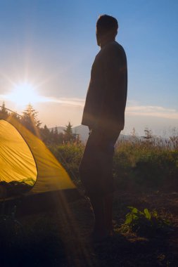 Gezgin adam bir çadır ve güzel su hayran yanında duruyor