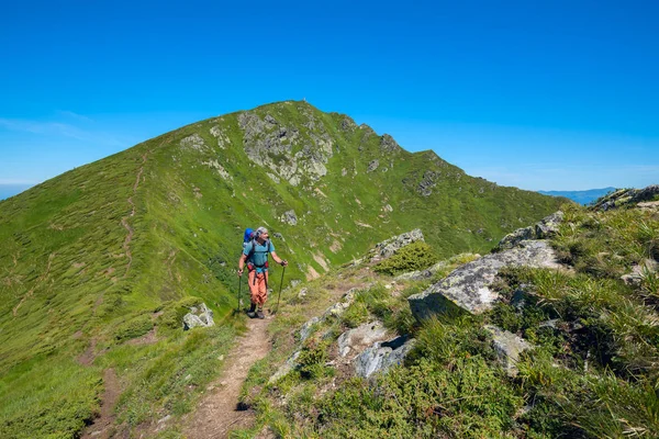 Reizigers man met rugzak gaat langs de bergkam — Stockfoto