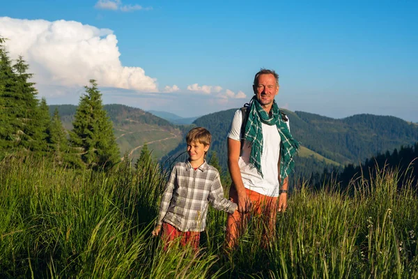 Viajantes alegres: um homem e um menino estão de pé em um meado alpino — Fotografia de Stock