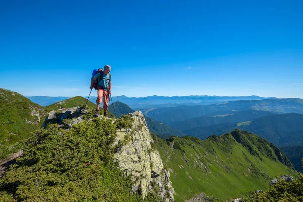 Wandelaar man met een rugzak staande op een rotsachtige klif — Stockfoto