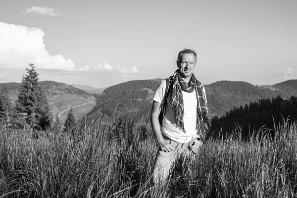 高山の牧草地で、スカーフを身に着けている夢の男が立っています。 — ストック写真