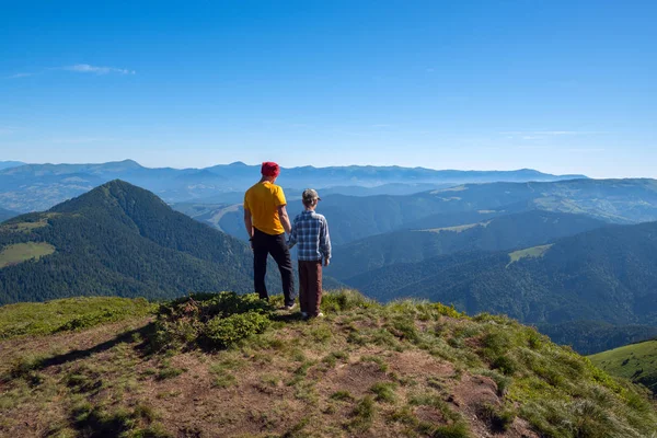 Pai e filho estão no pico e olham para a distância — Fotografia de Stock